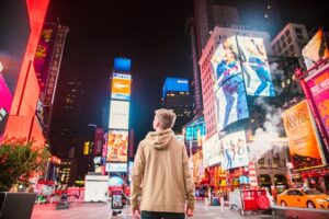 Man walking through busy city surrounded by neon advertising signs