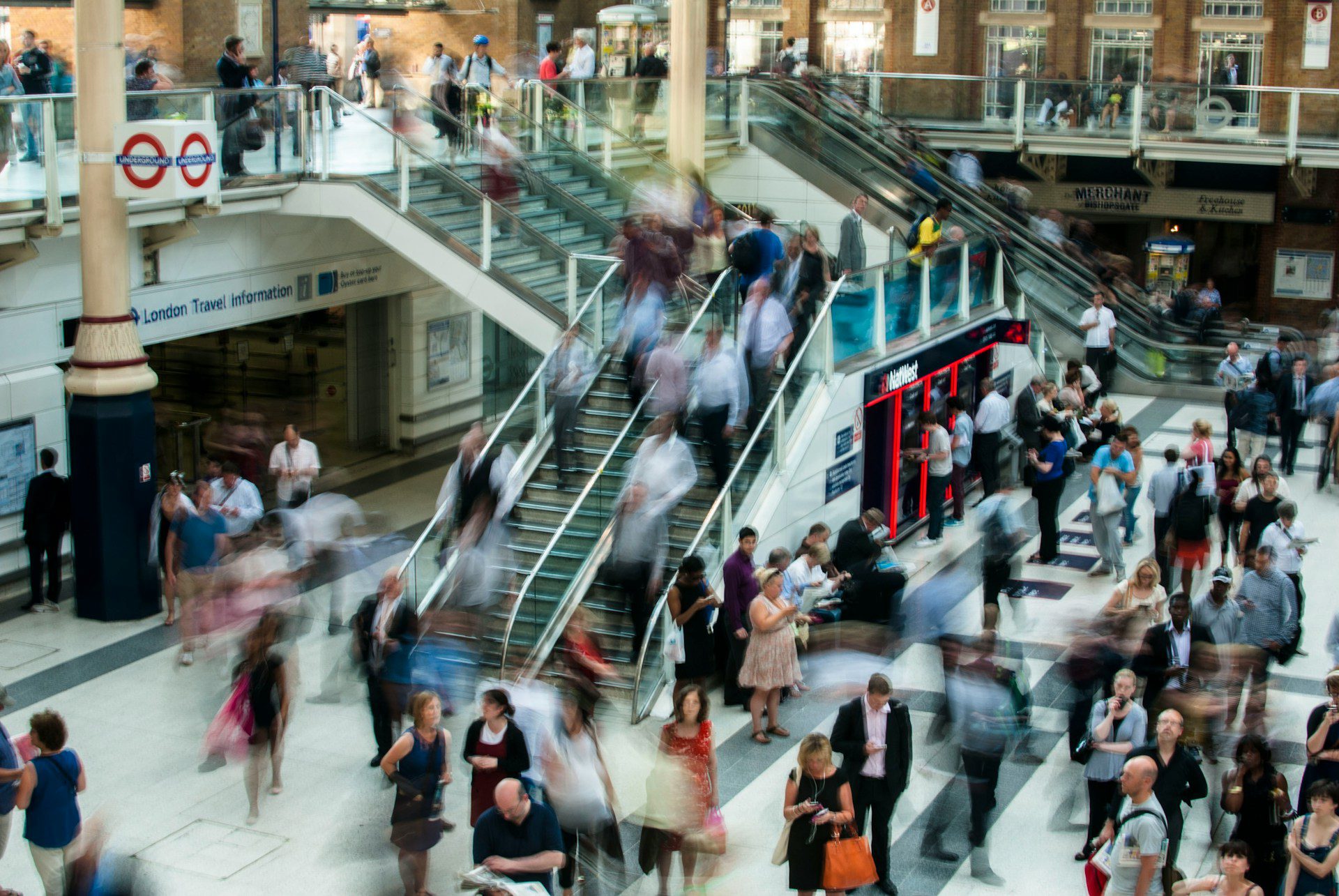 Bustling concourse and escalator, full of busy people