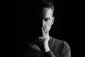 Man holding finger to lips in 'Shh' motion to indicate anonymity when securing a domain name