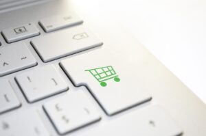 Computer keyboard with a green shopping cart button to denote selling a business with an attractive domain name