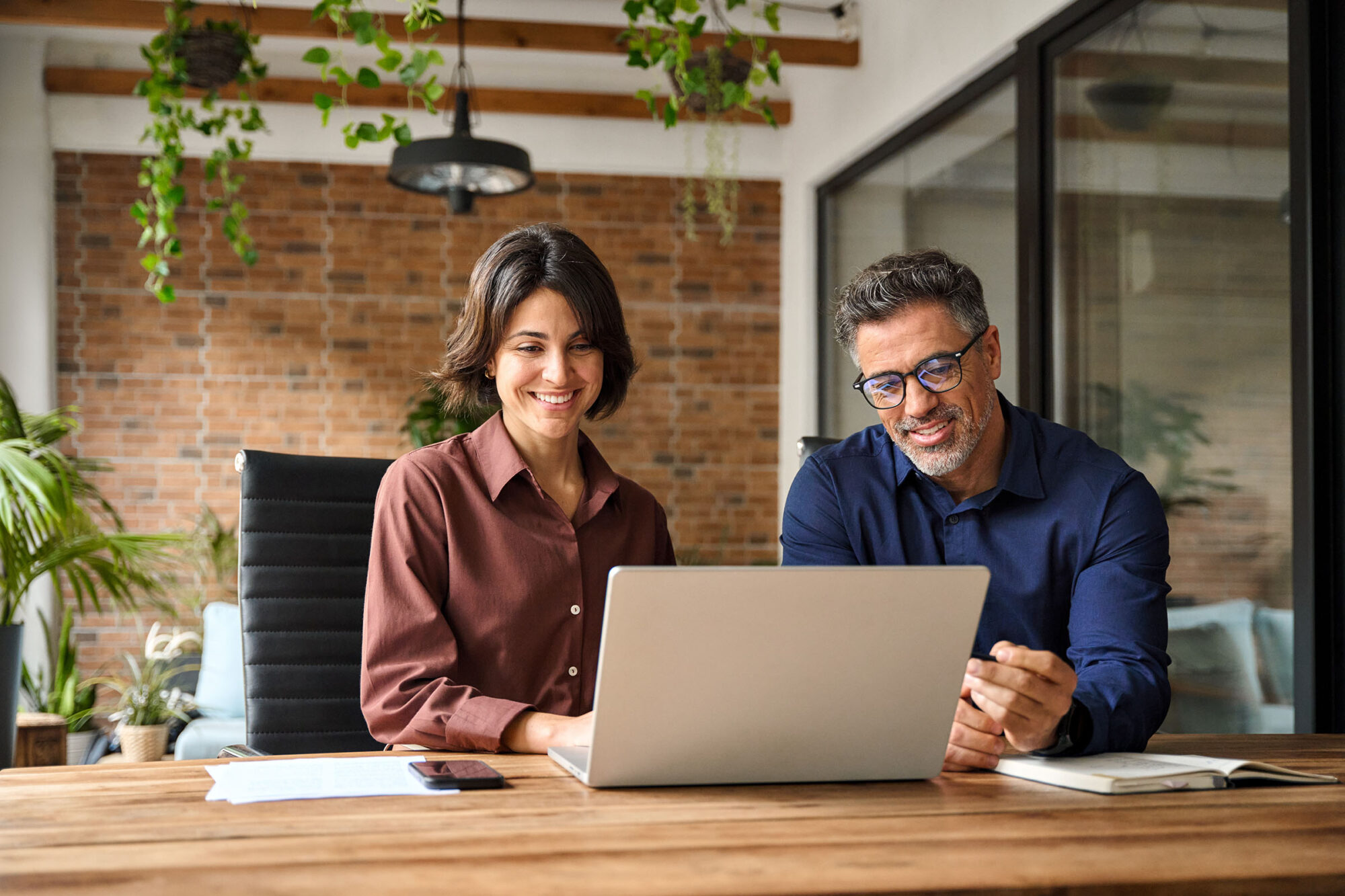 Man and woman in casual setting look at a laptop, as if investigating best places to buy a premium domain name