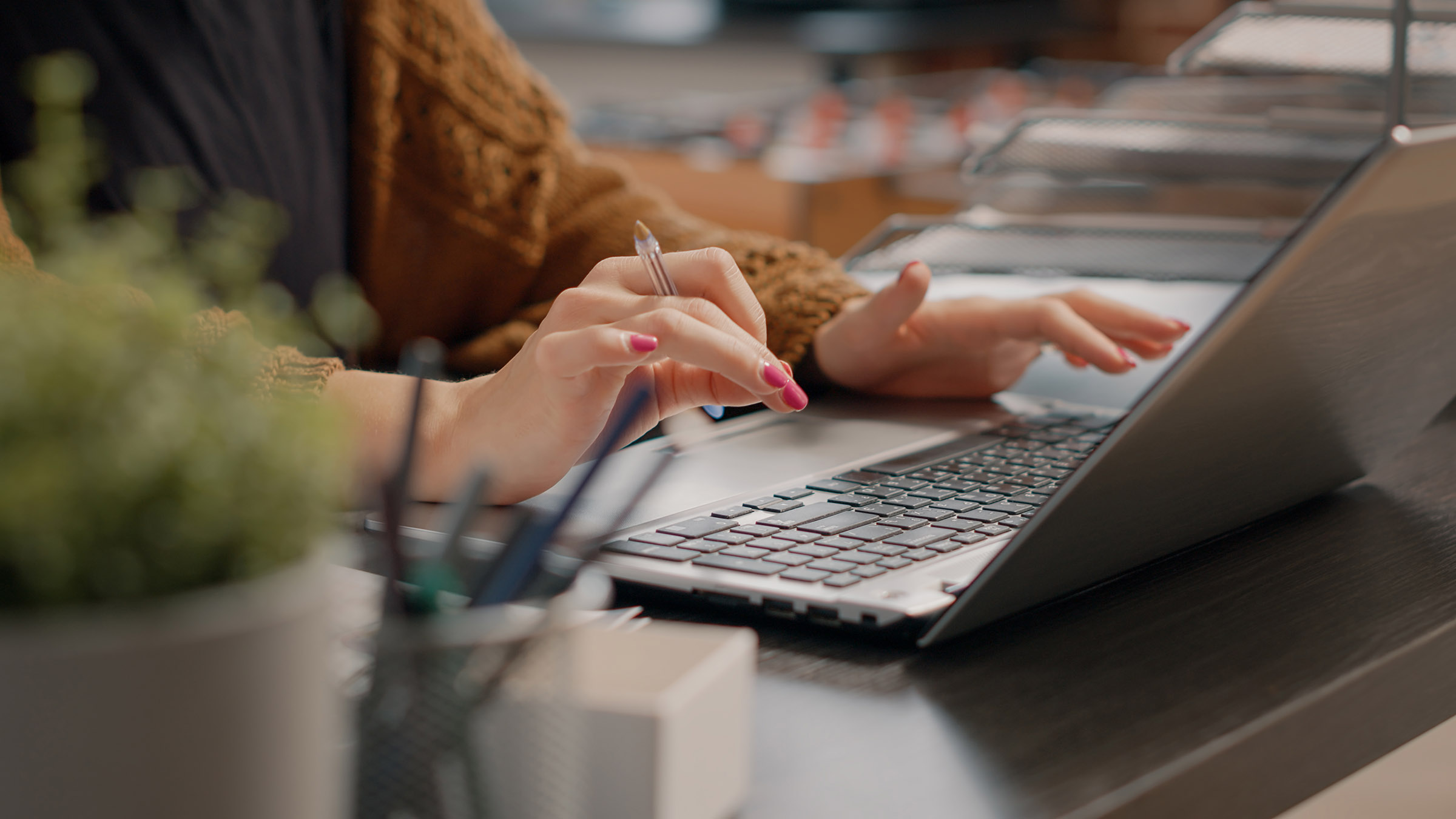 Close up of woman typing on laptop keyboard to indicate the importance of doing research when purchasing a domain name