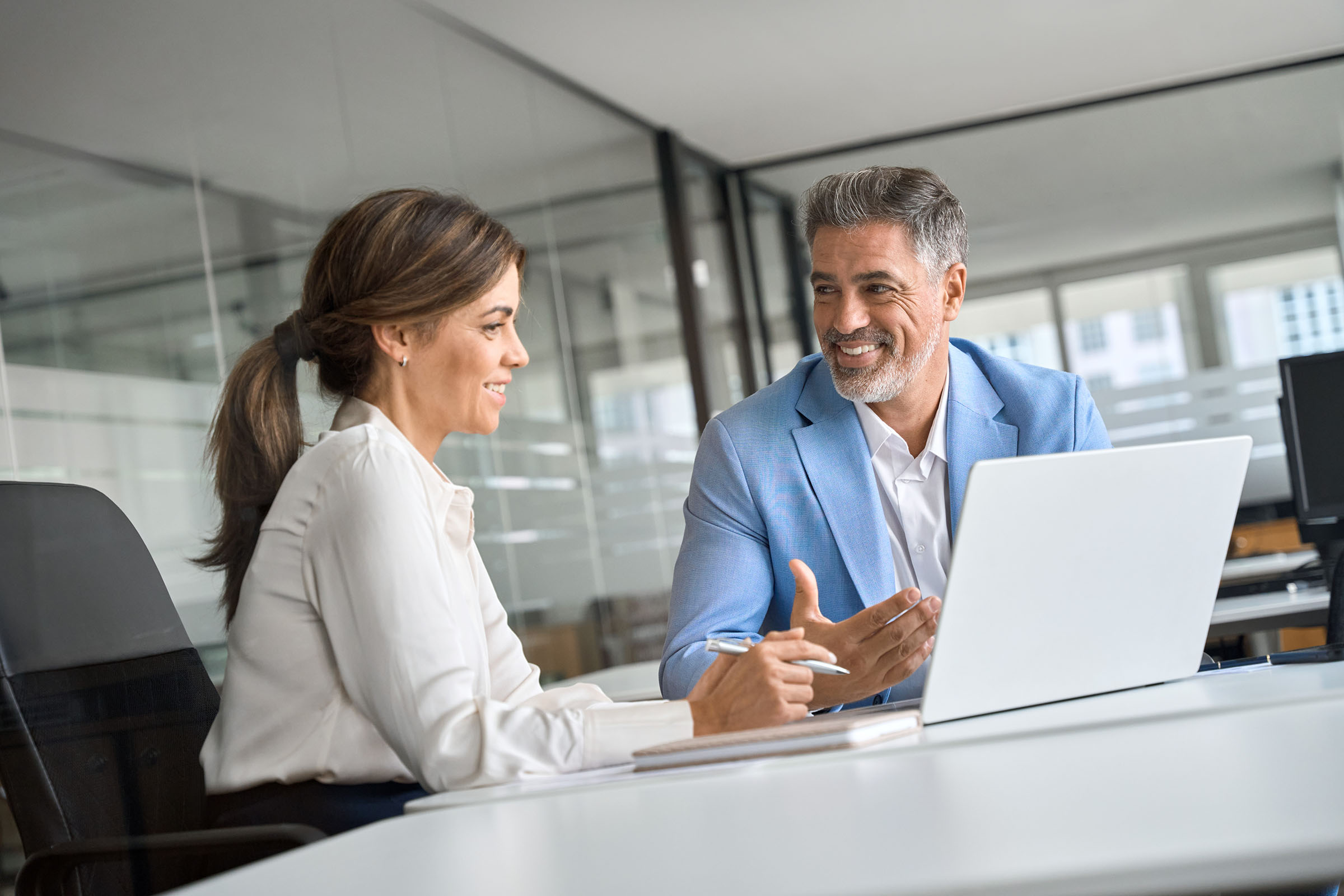 Professional looking man (on right) and woman (on left) studying computer as if in conversation about domain names