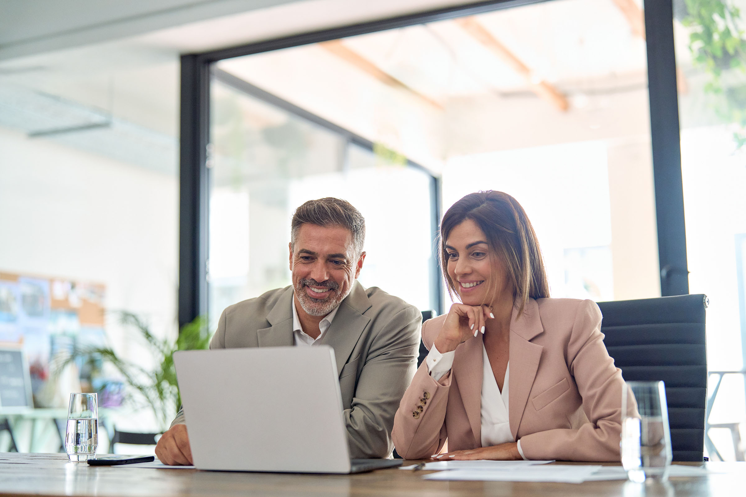 Two execs – one male, one female – face an open laptop to illustrate blog post about domain names