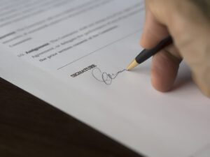 Paperwork being signed, denoting completed domain buy service transaction.