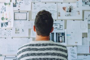 man staring at jumble of business names and notes on a board