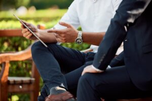 Two men (no faces seen) discussing a deal on a park bench