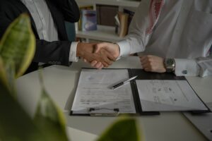 Close up (on arms) of two people shaking hands after successfully negotiating a deal